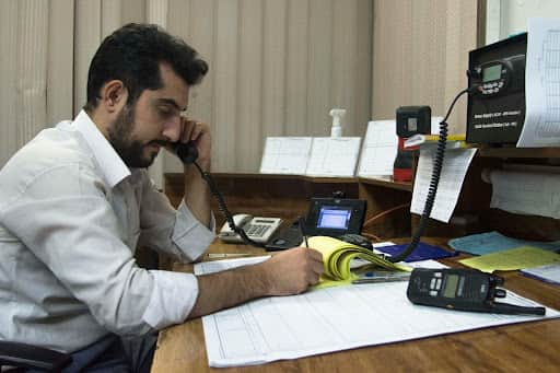 A professional uses a VoIP international business phone number to manage global clients and take notes at his desk.